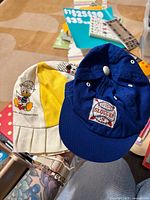 Both hats held in hand showing overall colors, designs, and sizes