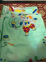 Folded mint-green fabric showing cartoon elephant with toys
