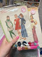 Front view of two sealed vintage sewing kits showing Simplicity pattern envelopes, buttons and price stickers