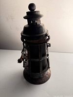 Side view of cylindrical metal lantern with wire cage and patina
