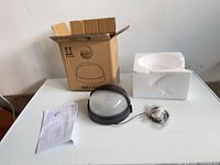 Box, foam insert, light fixture, manual, hardware pack on table