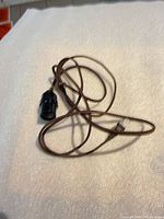 Coiled brown cloth-covered cord with socket visible