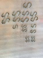 Overhead view of 15 chrome-plated steel S hooks arranged by size