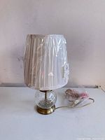 Full view of lamp with shade wrapped in plastic and cord
