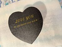 closed heart-shaped box top showing gold text