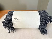 Rolled IKEA INGRUN throw showing front of sleeve label