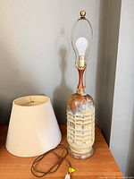 Lamp base, harp, finial, bulb, shade and cord on table