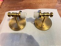 Front view of both sconces showing brushed brass finish, backplates and E26 sockets