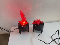 Both flame lights on tabletop, cords visible, one light operating