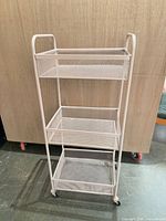 Front view of three-tier mesh metal cart on casters