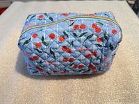 Front angled view of quilted cherry print cosmetic bag