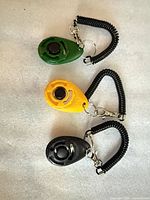 Front view of three clickers showing colors, buttons and straps