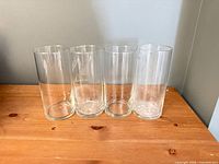 Front view of four clear glass tumblers standing side by side