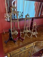 Group of brass-tone easels and wood stands on dresser