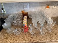 Countertop view showing entire assortment of clear and coloured vintage glassware