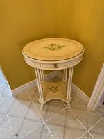Full view of oval accent table showing top floral design, drawer, legs, and lower shelf