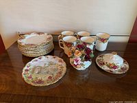 Full lot showing plates, mugs, floral ornament, covered dish