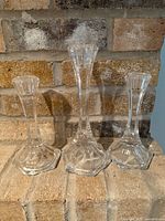 Three graduated crystal candlestick holders displayed side by side