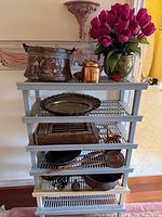 Full view of grey plastic shelf with copper and brass items displayed on all tiers
