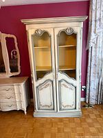 Front view of cabinet showing double doors with wire inserts and carved details