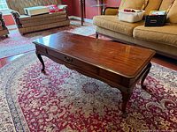 Full view of mahogany coffee table on rug