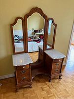 Full view of oak vanity showing tri-fold mirror, marble tops, drawers