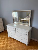 Front view of white six-drawer dresser with attached mirror