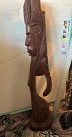 Full side view of carved wood sculpture showing profile and headdress