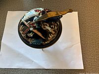 Top view of enamel bowl with lid showing painted design and handle