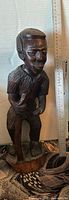 Front view of carved wood statue with ruler showing height