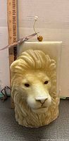 Front view of lion head candle with ruler for scale and intact wick
