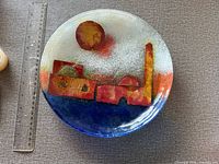 Front view of fused glass plate with skyline motif beside ruler