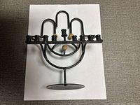 Front view of black metal Hamsa menorah showing nine candle cups and wood accents