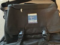 Front view showing flap with patch, buckles, shoulder strap and handles
