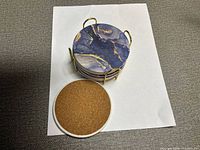 stacked blue marble-look coasters in gold rack with one coaster flipped to show cork back