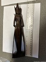 Rear view of hardwood figure beside ruler