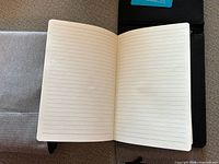 Open lined notebook atop grey and black cases