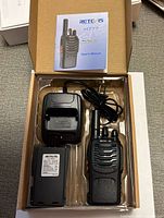 Opened box showing radio, battery, charger, cord, manual