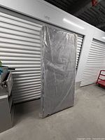 Front view of one boxed single box spring leaning against storage door