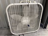 Front view of white Lasko box fan showing grille and blades