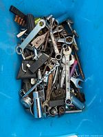 Blue bin filled with assorted wrenches, drill bits, sockets, hex keys and small hardware