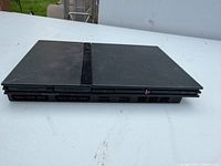 Front view of black PlayStation 2 Slim console showing controller and memory card ports