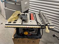Overall view of Ryobi 10-inch table saw on box showing fence and blade guard