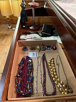 Drawer view showing necklaces, brooches, gloves, stands and box