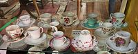 All twelve miniature cup and saucer sets displayed in cabinet