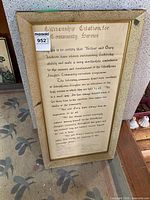 Full view of framed citation on floor showing gold frame and size reference