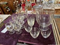 Full lot showing pitcher, two ice buckets, stemmed emblem glasses, small tumblers