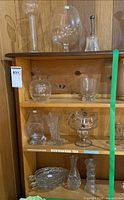 Full shelf view showing assorted glass pieces on four tiers