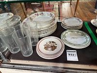 Group view of stacked plates and ribbed tumblers inside display case