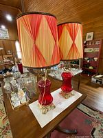 Both lamps showing red glass bases, gold-tone metal and shades